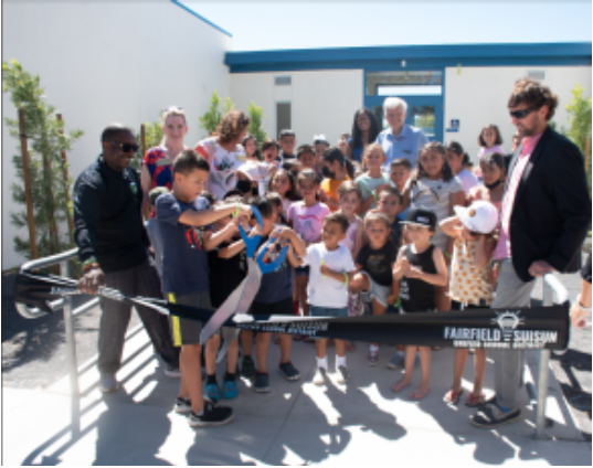 Group of students and community members standing in front of new school